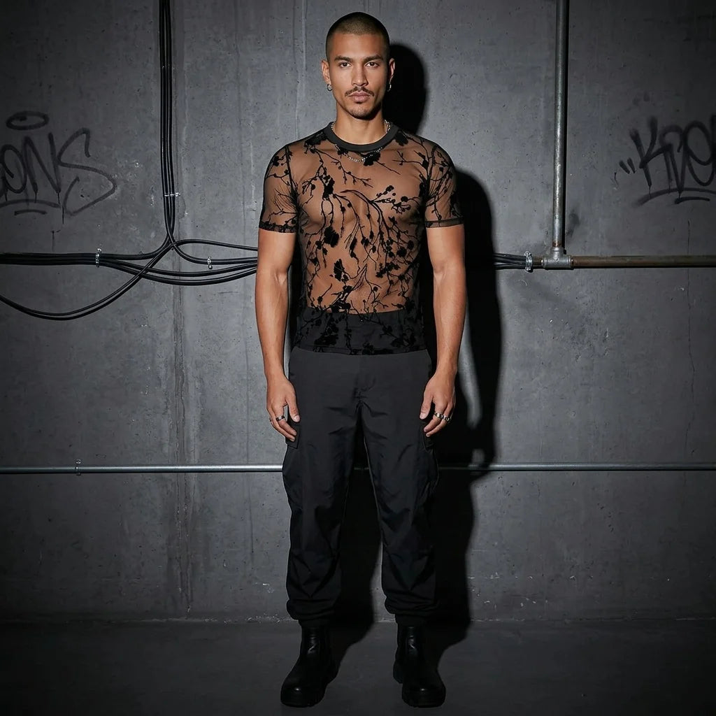 Ganzkörperansicht, Model im Shadow Bloom Meshshirt, Techno- und Rave-Mode, urbaner Hintergrund.