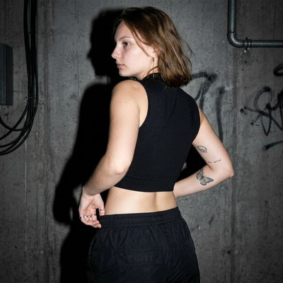 Seitenansicht des schwarzen Rave Zip Tops, Model in urbanem Setting