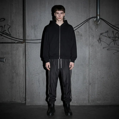 Model frontal in Reflective Nightflow Hose, schwarz, ideal für Techno-Events.